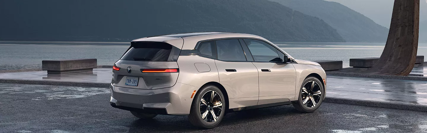 Rear view of a 2026 BMW iX parked with the ocean in the background