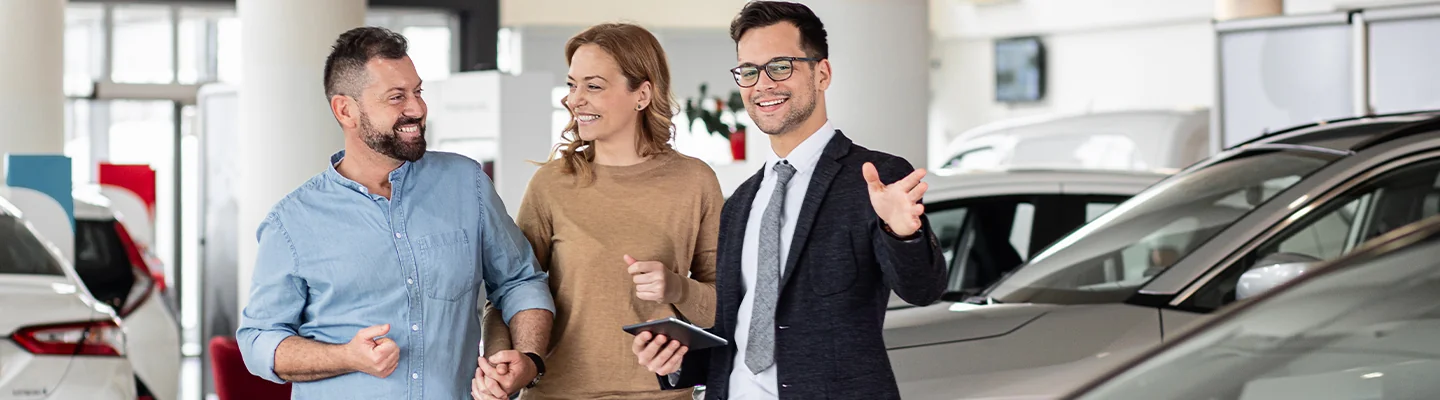couple speaking with car salesperson in dealership beening shown car models