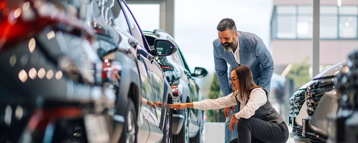 Two people looking at new vehicles at a car dealership