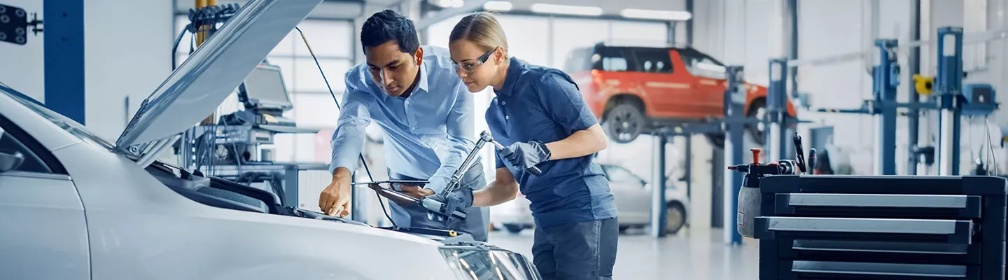 mechanic and tech working under the hood of a vehicle