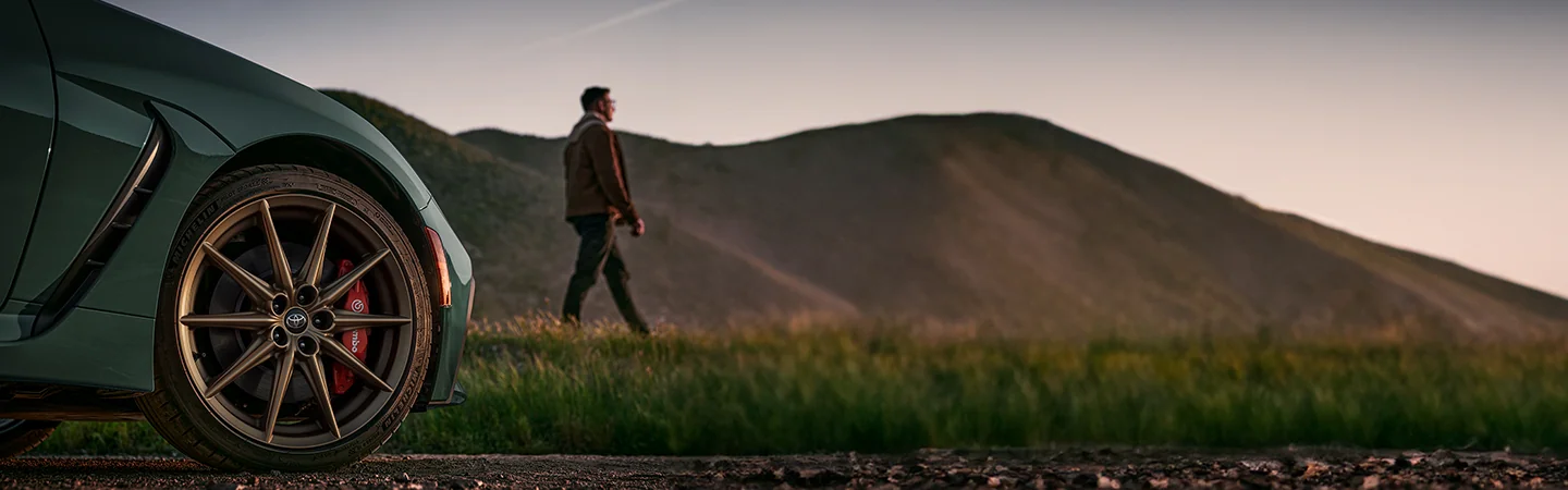 Man standing in front of 2025 Toyota GR86 with mountains in the background