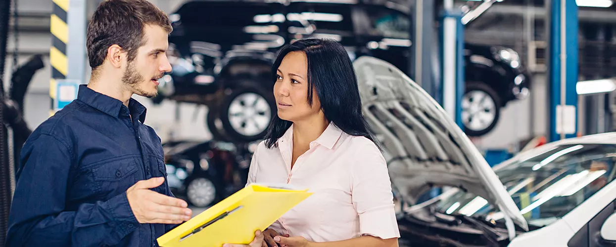 Service mechanic talking to a customer about their vehicle