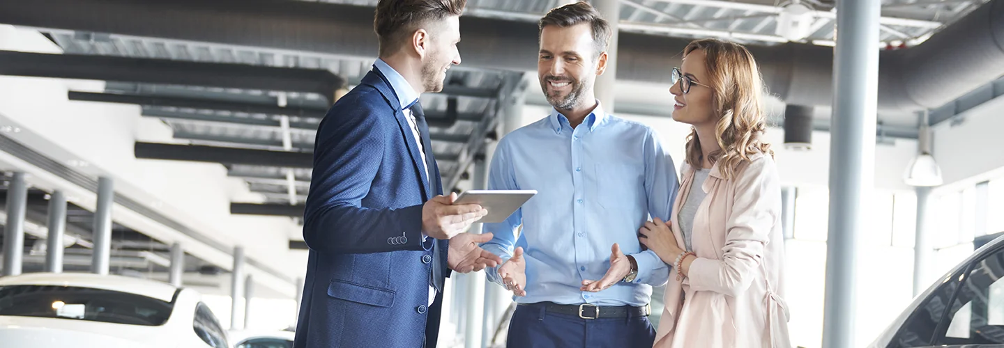 Car salesperson speaking with customers about leasing vs. buying a BMW
