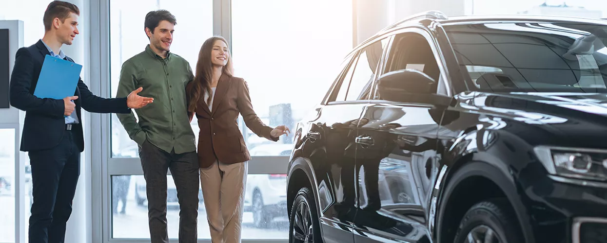 Car salesman showing a couple a new vehicle