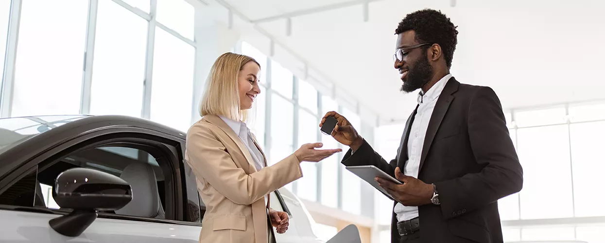 Car salesman handing a customer a new set of car keys