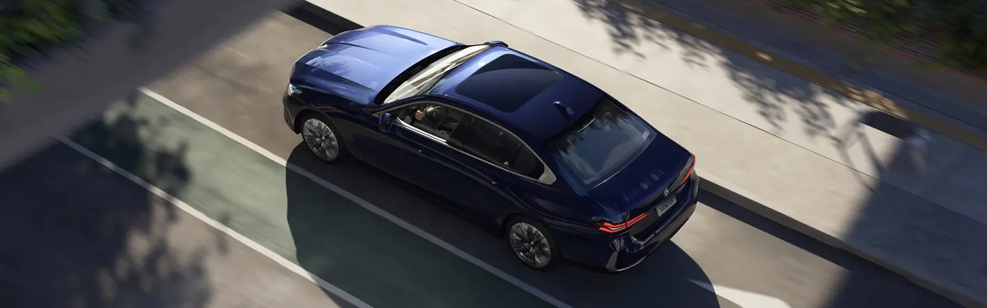 Side view of a parked blue 2025 BMW 5 Series in front of a building