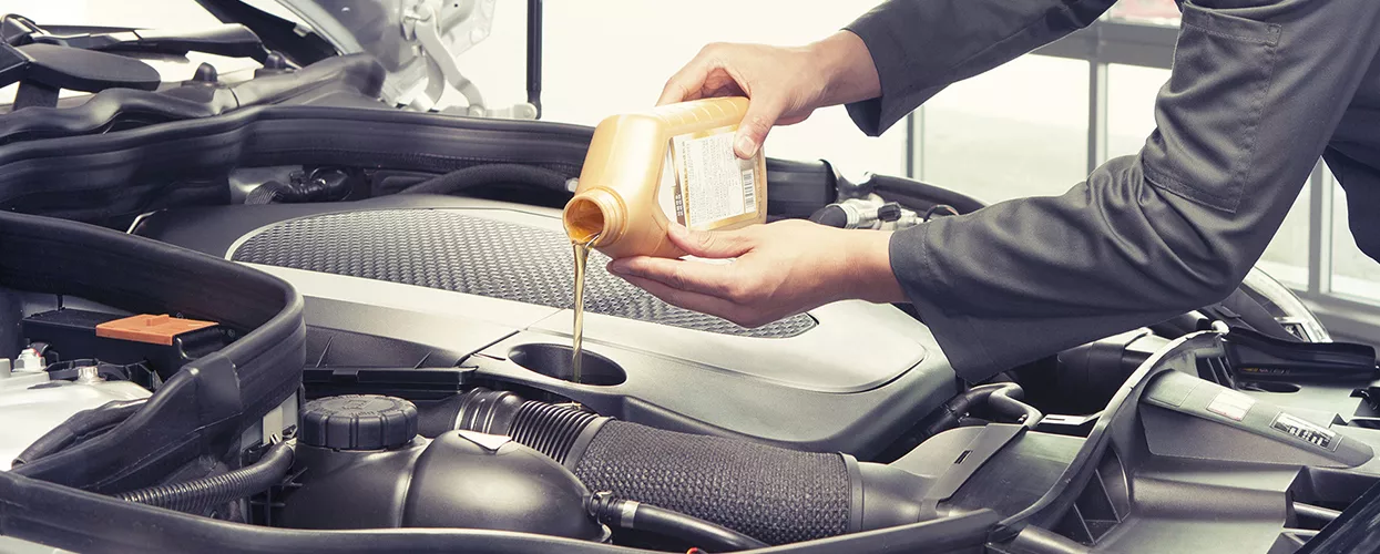 Technician performing an oil change on a Honda vehicle in a service bay