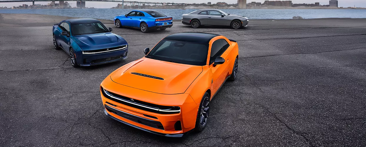 Dodge Charger lineup featuring multiple performance muscle cars parked along the waterfront, showcasing modern design and electric performance
