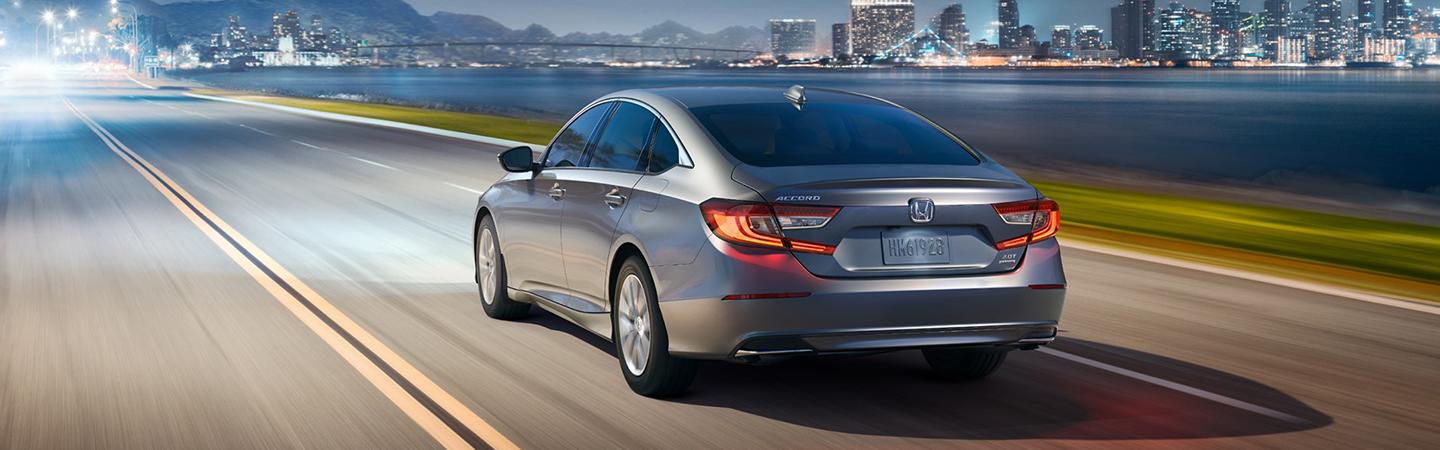 2022 Honda Accord rear view in evening along shoreline with city skyline in distance