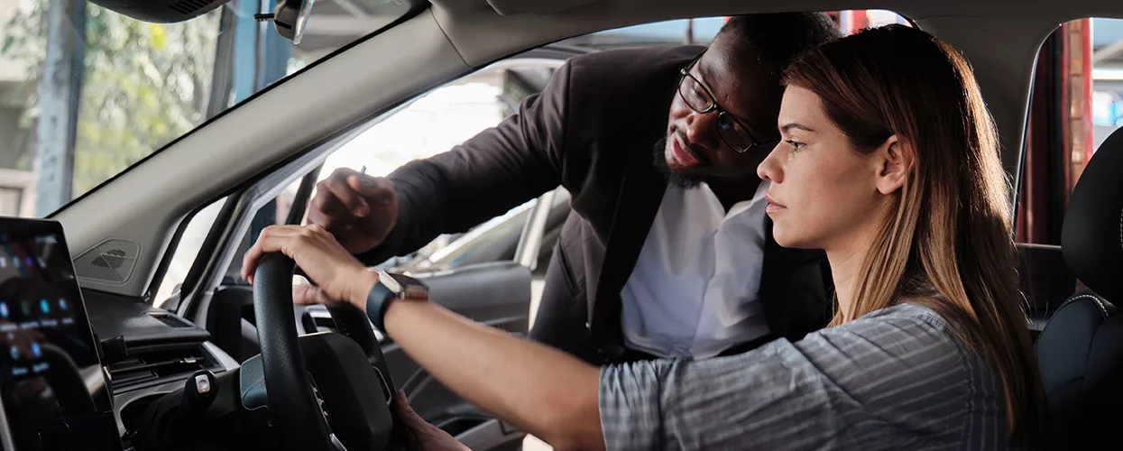 Car salesman showing a customer the inside of a new vehicle