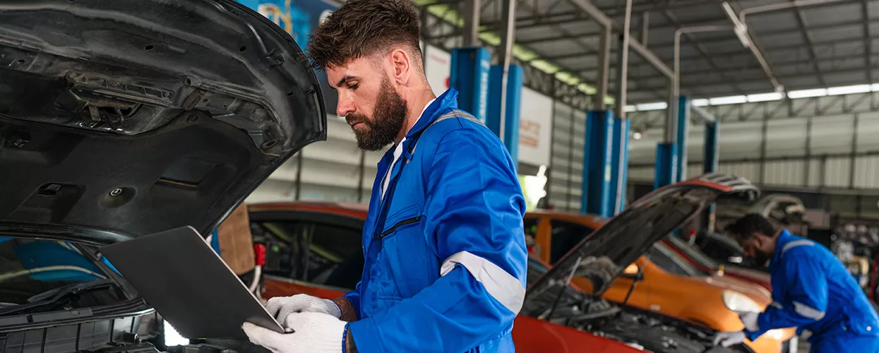 Service mechanic working under the hood of a vehicle