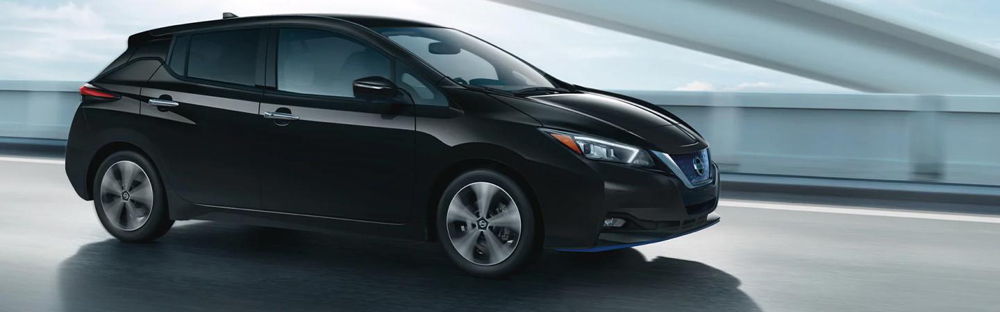 Black 2022 Nissan Leaf driving on a bridge