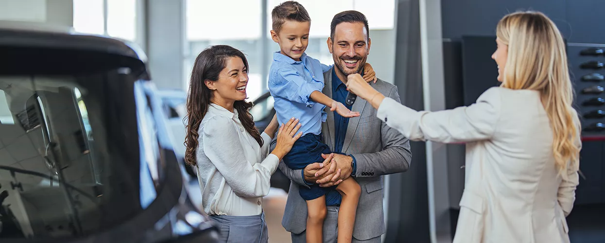 Family being handed new keys at a car dealership