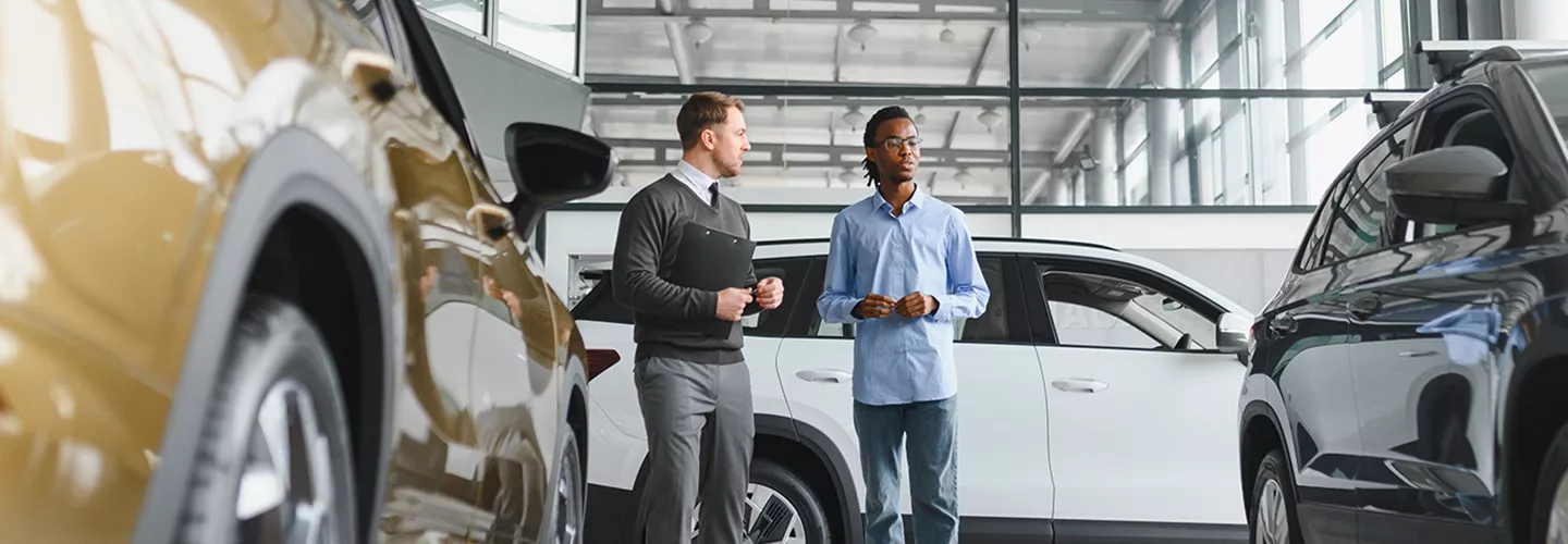 Sales person walking though a showroom with a customer talking about Toyota Hybrid vs. Gas Cost Comparison and Long-Term Toyota Ownership Costs