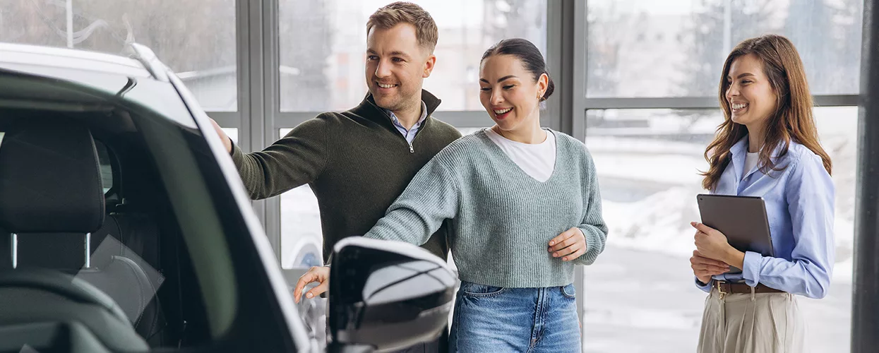 Car salesman walking through a car dealership with two customers