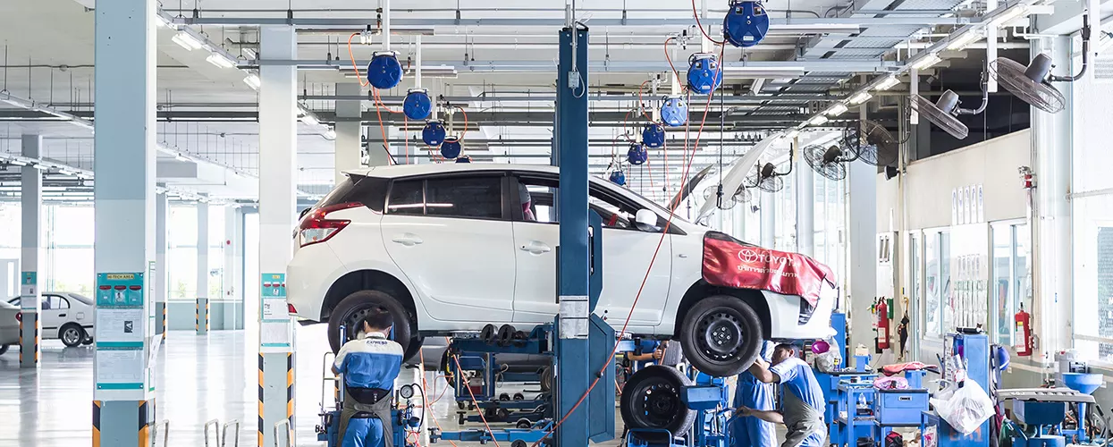 Auto mechanic working on a car on lift in service bay