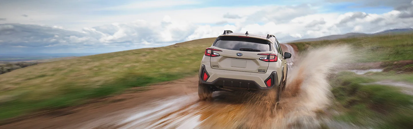 rear view of a white 2026 Subaru Crosstrek Hybrid Sport driving in mud