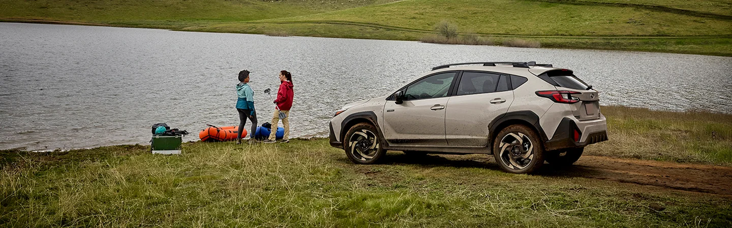 2026 Subaru Crosstrek Hybrid Sport parked by a lake with two people standing by lake