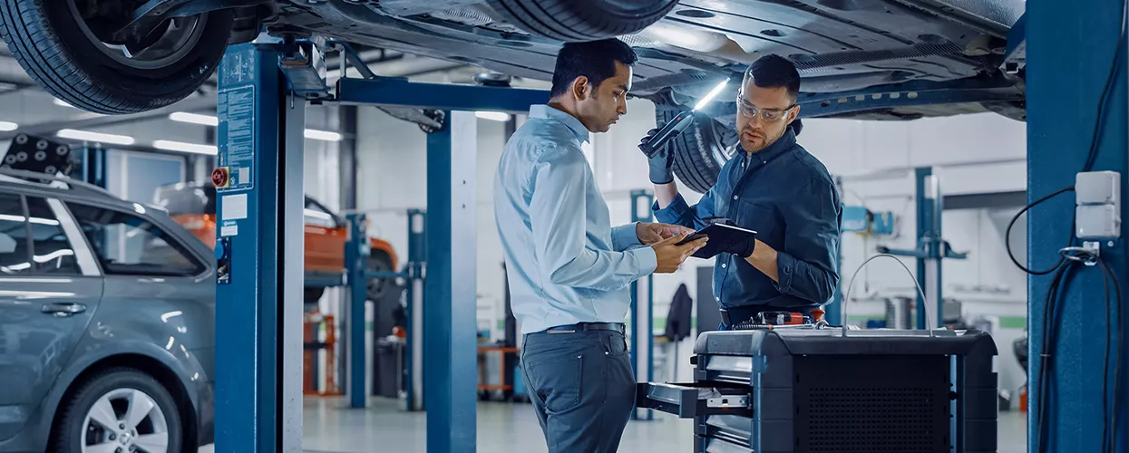 Service mechanics looking under a lifter car