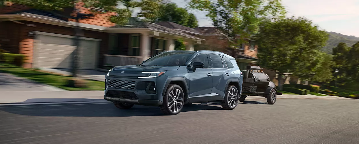 Toyota SUV towing a trailer on a residential street, demonstrating towing capability, utility, and everyday performance