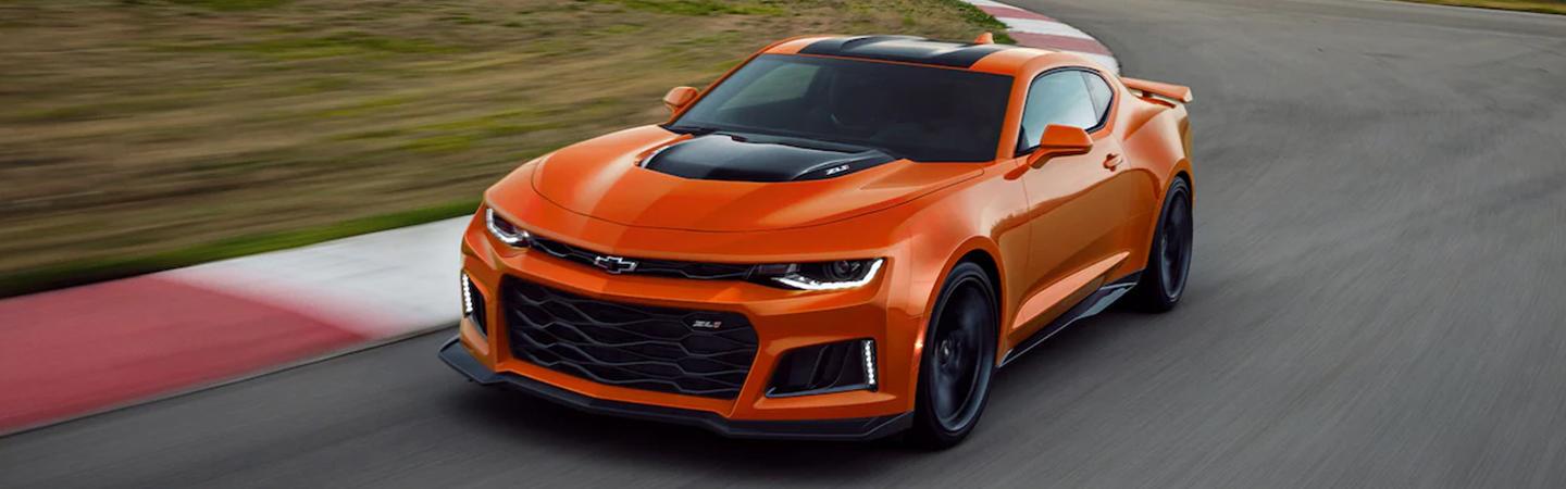 Orange 2022 Chevy Camaro in motion taking curve on race track