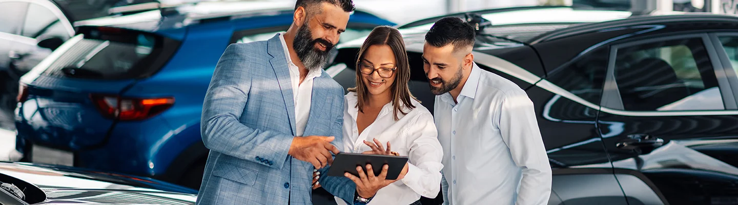 couple speaking with car salesman about car purhcase looking very happy