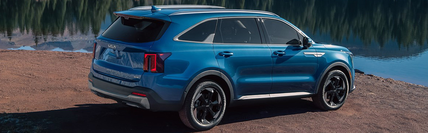 Side view of a parked blue 2025 Kia Sorento Hybrid next to a lake