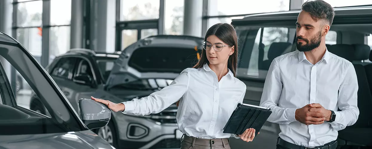 Car saleswoman showing a customer a vehicle at a car dealership