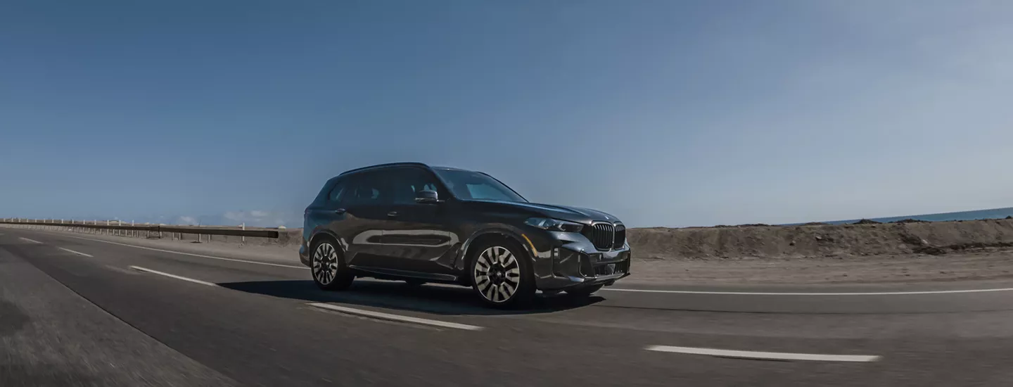 2026 BMW X5 driving on a road with the desert in the background