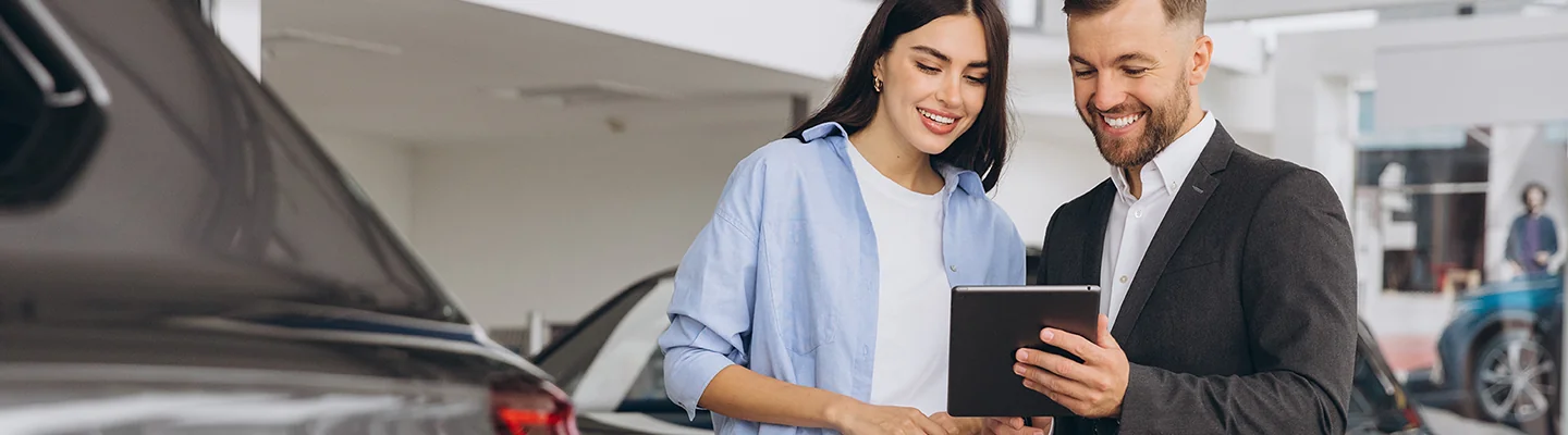 a car buyer speaking with salesperson both pleased with information on tablet they are going over