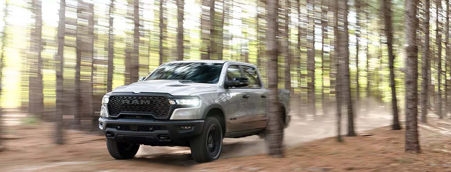 2026 RAM 1500 driving through the woods with dust kicking up