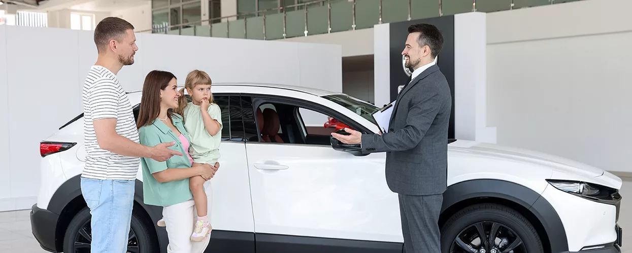 family of three speaking with car salesperson in dealership