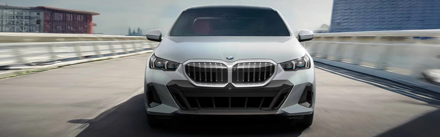 Front view of a 2025 BMW 5 Series driving on a road