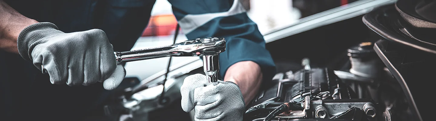 auto mechanic with rachet tool working on a car