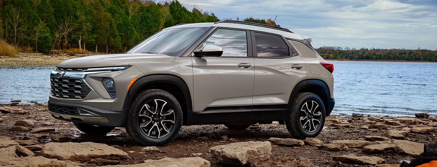 Side view of a tan 2026 Chevrolet Trailblazer parked at a rocky lake