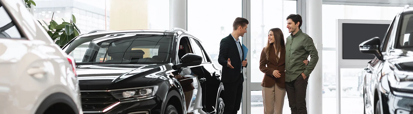 couple speaking with car salesperson in showroom