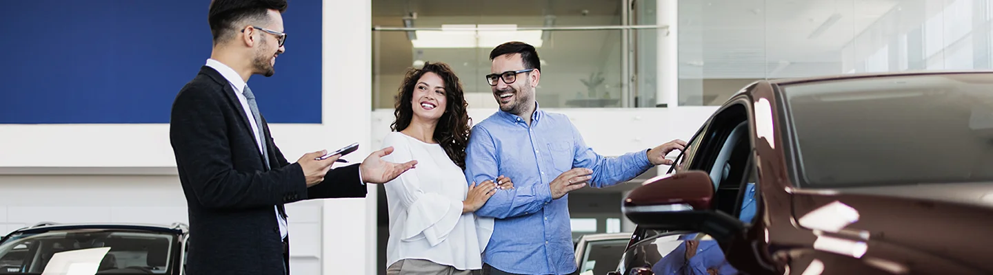 couple talking with car salesman in showroom