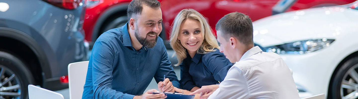 couple speaking with car salesman in showroom about trading in a car