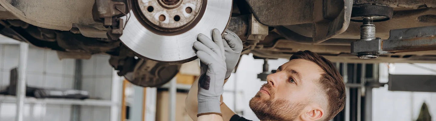 car mechanic works on car brakes on lift