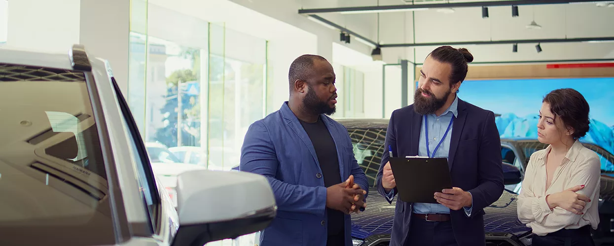 Car salesman showing a couple a new vehicle