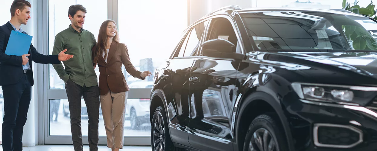 Car salesman showing a couple a new vehicle