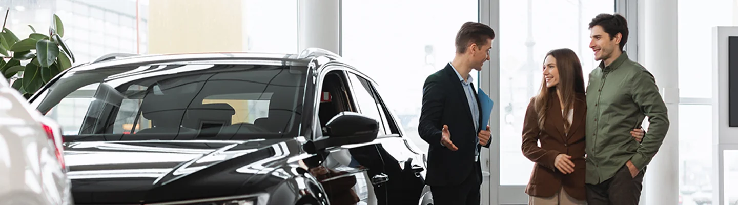 Sales person showing a couple cars in dealership