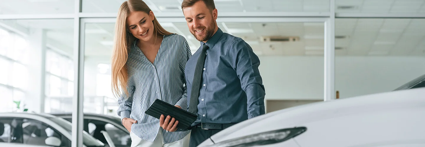 a car salesperson showing a car to another person in showroom