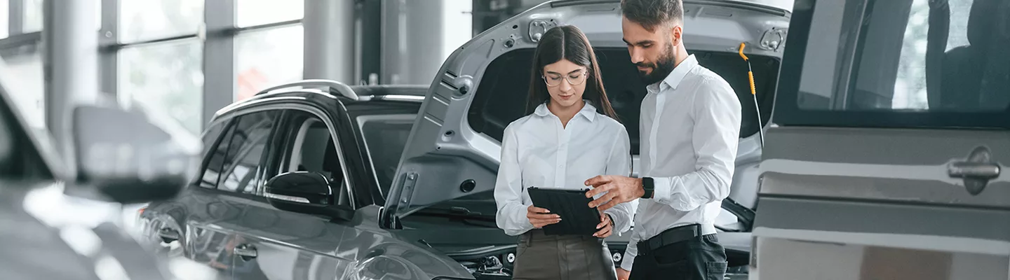Salesperson showing information about a used car to a customer