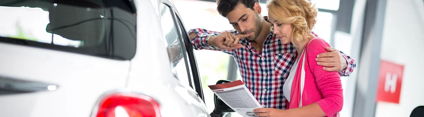 couple looking over details of a car purchase in showroom