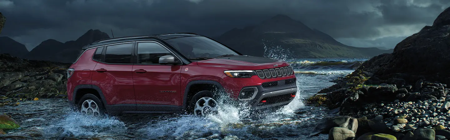 Front view of a white 2025 Jeep Compass driving in the rain