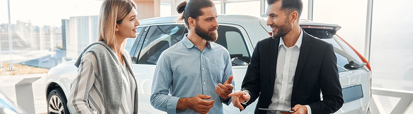 Hyundai salesman talking with a couple while holding a smart table next to a car