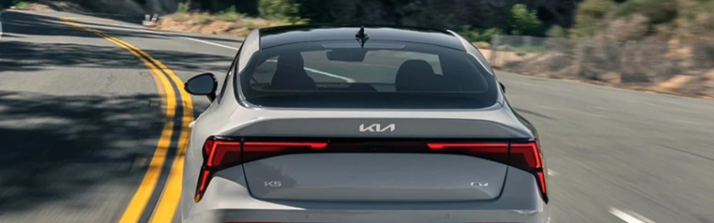 Close up back viwe of a gray 2025 Kia K5 driving on a road