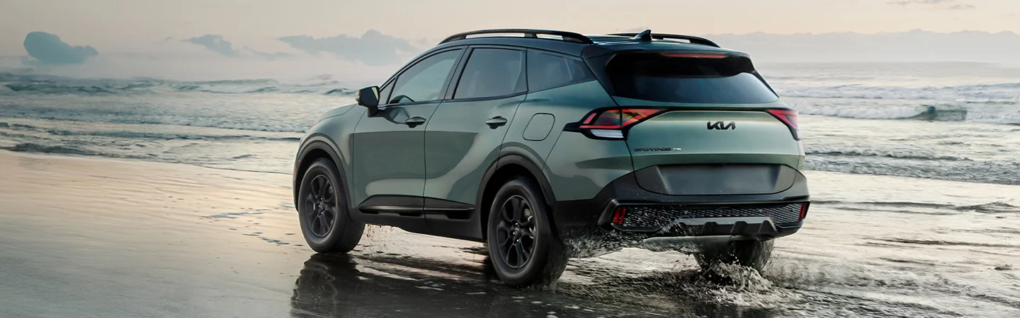Back view of a 2025 Kia Sportage driving on the beach