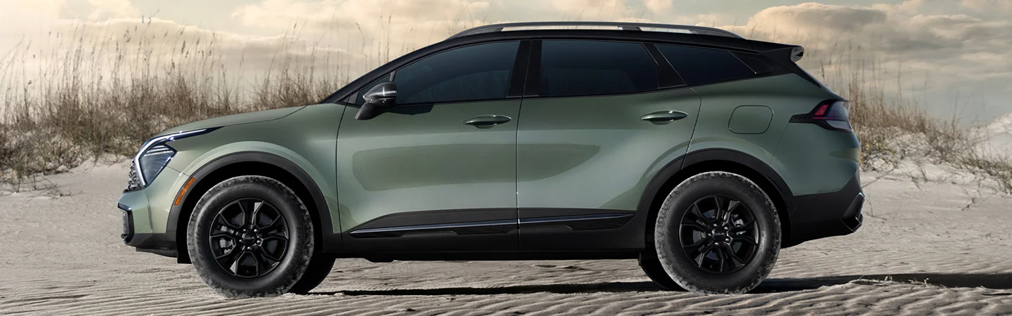 Side view of a green 2025 Kia Sportage parke don the beach